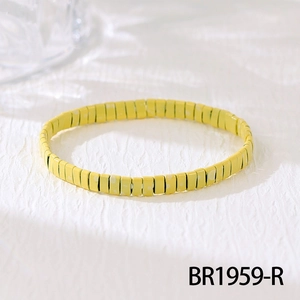 Close-up of a yellow stretch bracelet featuring flat rectangular beads with white polka dots