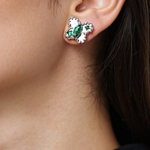 Detailed view of silver butterfly earring with green zircon and white enamel on ear