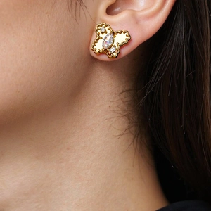 Close-up of golden butterfly stud earring with sparkling zircons worn by a model