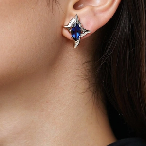 Close-up of four-pointed star earring with marquise blue zircon on model's ear