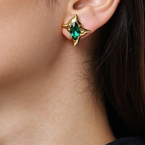 Close-up of starburst stud earring with green marquise zircon on a model's ear