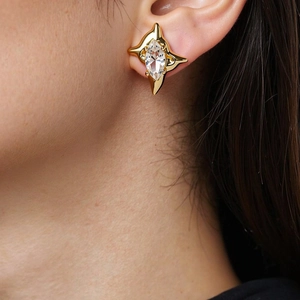 Detail of gold star stud earring with marquise-cut zircon on model's ear