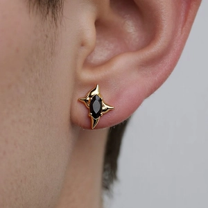 Close-up of four-pointed star earring with black marquise gem in gold finish