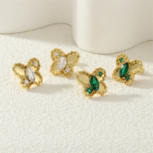 Detailed shot of butterfly earrings with emerald and clear stones in gold finish