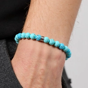 Detailansicht eines Türkis-Perlenarmbands mit silberner Gravurperle an einem Handgelenk