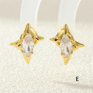 Detailed close-up of golden four-pointed star stud earrings with marquise-cut zircon
