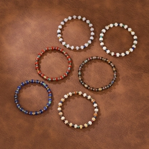 Detailed close-up of six handmade bohemian bead bracelets on brown leather background