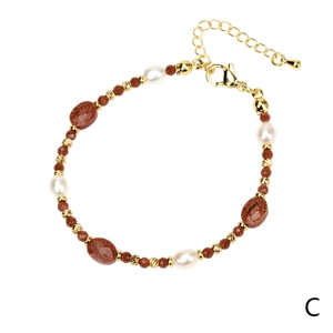Detail van kralenarmband met witte parels, goudsteen kralen en gouden karabijnsluiting