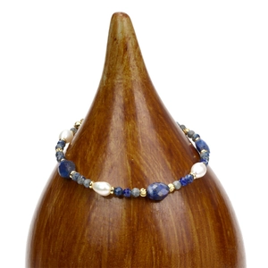 Detail van lapis lazuli kralen en barokparels op een houten displaystandaard voor sieraden