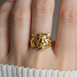 Macro close-up of a hollowed-out golden tiger head ring with detailed metal engraving