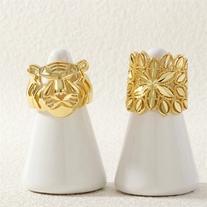 Detailed view of gold tiger head and floral geometric hollow rings on white displays