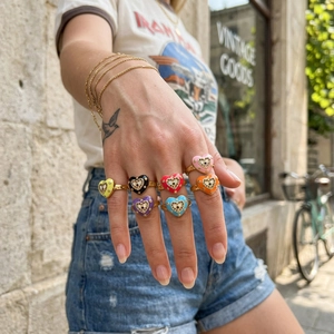 Colorful enamel heart evil eye rings with crystal accents on a model's hand