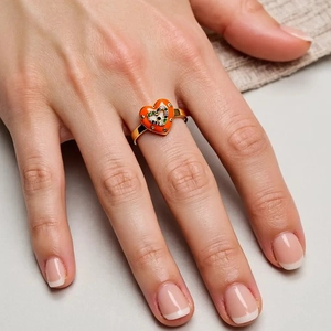 Close-up of golden heart ring with orange enamel and colorful devil's eye gemstones