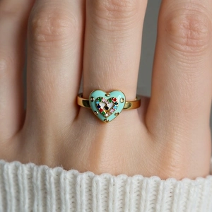 Macro detail of gold devil eye heart ring featuring colorful enamel and inlaid gemstones