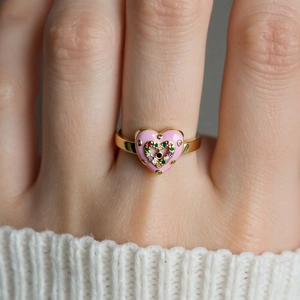 Detail of a pink heart enamel ring with multi-color zircon stones on a gold-plated band