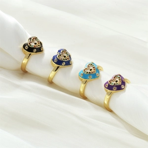 Detail of four heart-shaped evil eye rings with colorful enamel on white silk