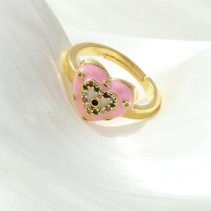 Macro view of gold heart ring with pink enamel, colored crystals and evil eye detail