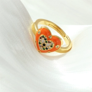Close-up of heart-shaped evil eye ring with orange enamel and colorful zircons