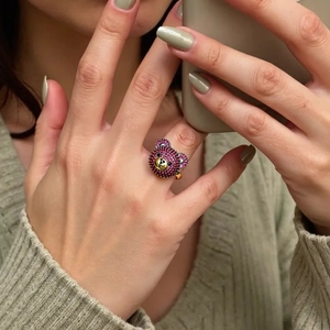 Detail eines süßen 3D-Bärenrings mit roten Zirkonia an Hand mit grünen Nägeln