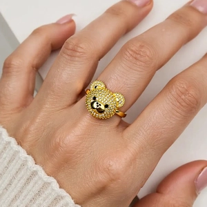 Nahaufnahme eines goldenen Teddybär-Rings mit Zirkonia-Besatz an einer Hand