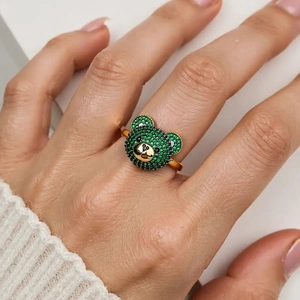 Detail eines Goldbärenrings mit grünen Zirkonia-Mikropavé auf einer Modellhand