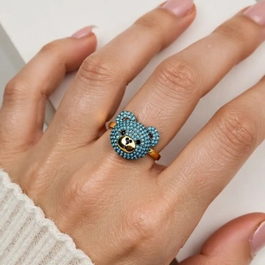 Detailaufnahme eines süßen goldenen Bärenrings mit hellblauen Zirkoniasteinen im Micropavé