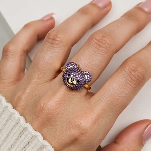 Nahaufnahme eines Goldrings mit Bärenkopf, besetzt mit violetten Zirkoniasteinen