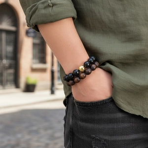 Gros plan de bracelets pour hommes en perles noires mates et bois sombre portés par un mannequin