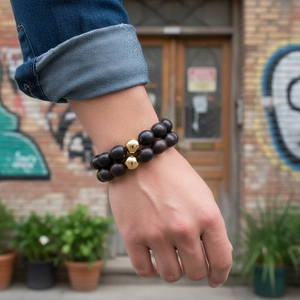 Gros plan de bracelets en perles de bois avec accents métalliques dorés au poignet