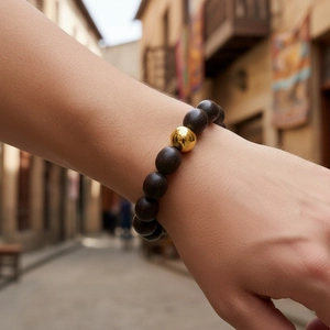 Détail d'un bracelet de perles en bois avec des perles sombres et une perle dorée