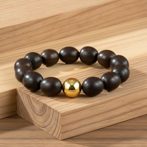 Détail d'un bracelet en perles de bois avec une perle dorée sur un support en bois