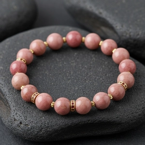 Detailed view of pink semi-precious stone beaded bracelet with gold spacer beads and crystals.