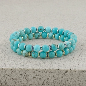Gedetailleerde opname van dubbelstrengse turkoois kralenarmband met metalen afstandshouders.