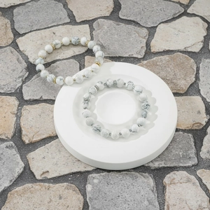 Detail shot of white semi-precious stone beaded bracelets with metal spacers on dish.