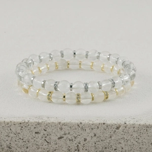 Gedetailleerd uitzicht op stapelbare heldere kristallen kralenarmbanden met metalen spacers.