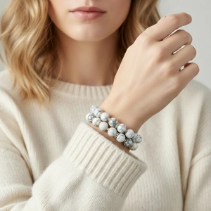 Close-up detail shot of white marble bead layered stretch bracelet with gold spacers.