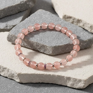 Detailopname van een charmante roze kralenarmband met zilveren spacers op steen.
