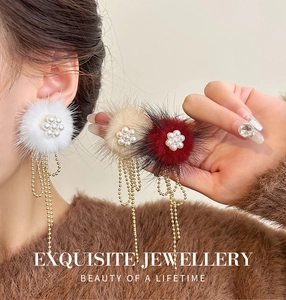 Detail of plush earrings with faux pearl flower and long golden metal fringe tassels