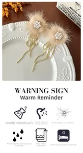 Detailed macro view of beige plush earrings with pearl petals and golden tassel chains