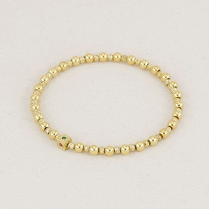 Golden beaded bracelet featuring textured spheres and a gemstone-inlaid cube pendant