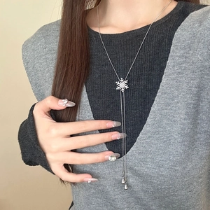 Elegante silberne Schneeflocken-Halskette mit Zirkon-Kristallen auf grauem Strick