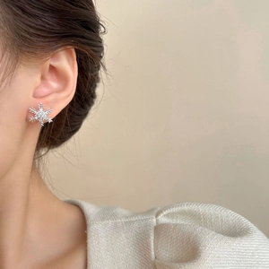 Elegantes pendientes de copo de nieve con circonitas usados en la oreja de un modelo