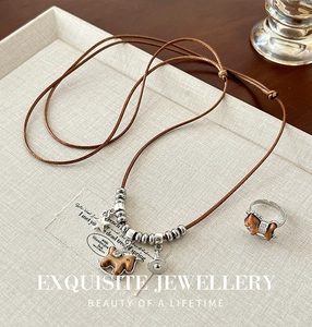 Close-up of vintage wooden horse pendant necklace and matching ring on a soft linen texture