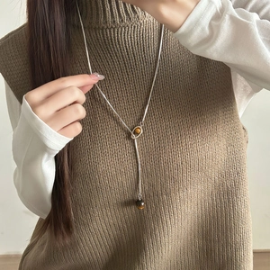 Collana lunga a Y con pietra occhio di tigre e catena d'argento su una modella