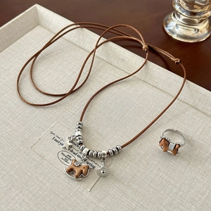 Vintage wooden rocking horse pendant necklace and matching ring on a textured tray