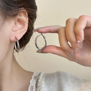 Primo piano di orecchini a cerchio ovali in argento minimalisti indossati da modella