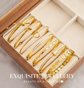 Dettaglio del set di bracciali a nodo dorati e margherite in una scatola portagioie