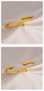 Dettaglio macro del design a nodo su bracciali aperti in acciaio dorato con raso