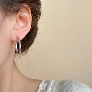 Orecchini a cerchio ovali minimalisti in argento mostrati su modella per un look chic
