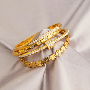 Set di tre bracciali in acciaio inossidabile dorato con cristalli e motivi a margherita